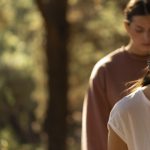 Two women stading behind each other in a forest