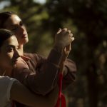 Two women holding hands in a forest